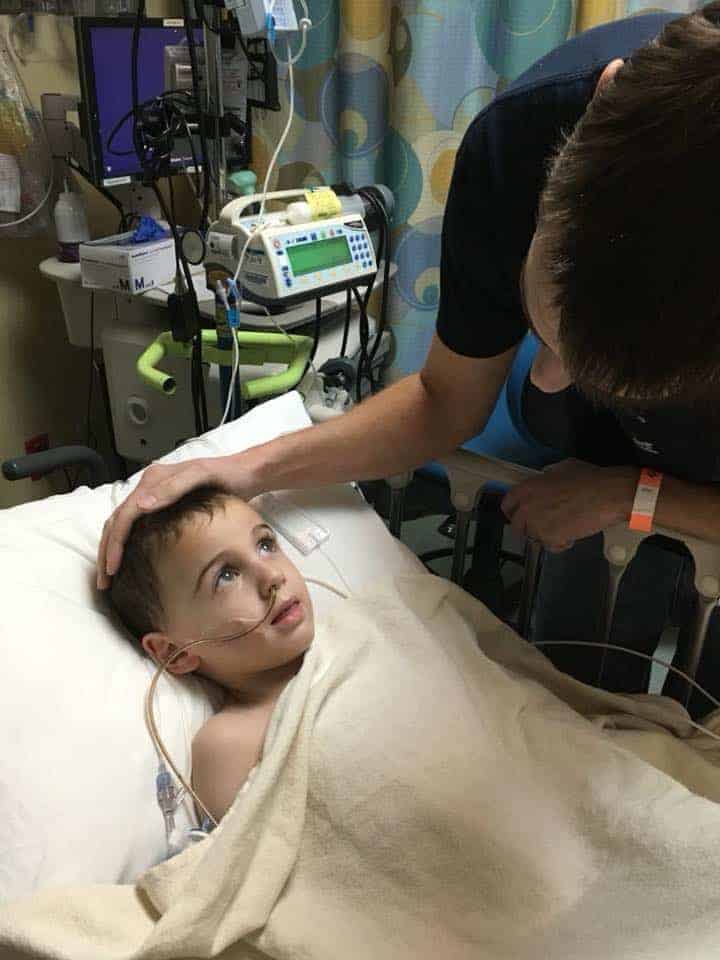 dad looking over son in hospital bed